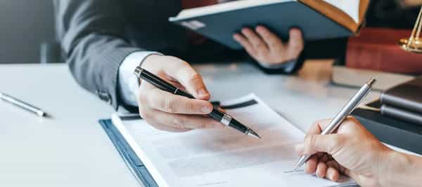 To hender med hver sin pen som skriver på et ark